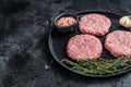 Raw chicken turkey patty, minced meat cutlets on a plate with thyme. Black background. Top view. Copy space