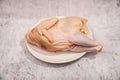 raw chicken on white plate on gray cement background