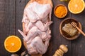 Raw chicken wings with ingredients for cooking: hohey, orange fruit, garlic, olive oil, kari on a wooden cutting board over