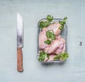 Raw chicken wings with parsley in a transparent bowl with a kitchen knife on rusti? wooden background top view close up