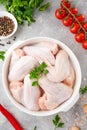 Raw chicken wings in a white dish with fresh herbs, spices for cooking on a gray concrete background. Top view, copy space Royalty Free Stock Photo