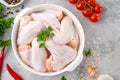 Raw chicken wings in a white dish with fresh herbs, spices for cooking on a gray concrete background. Top view, copy space Royalty Free Stock Photo