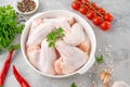 Raw chicken wings in a white dish with fresh herbs, spices for cooking on a gray concrete background. Top view, copy space Royalty Free Stock Photo