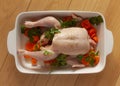 Raw chicken withwith vegetables and olive oil in a baking dish ready to be prepared for cooking. Top view image on wooden backgrou Royalty Free Stock Photo