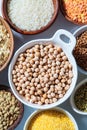 Raw chickpeas in white bowl. Various dry cereals and legumes in white and wooden bowls, white background. Vegan protein concept Royalty Free Stock Photo