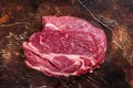 Raw Chuck eye roll beef steak on butcher table. Dark background. Top view