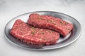 Raw chuck flatiron beef steaks with thyme leaves on metal serving plate flat lay on light gray background Royalty Free Stock Photo
