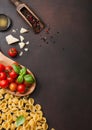 Raw classic conchiglie pasta with parmesan cheese and tomatoes, salt and pepper with oil on brown background Royalty Free Stock Photo