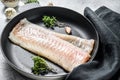 Raw cod fillet with thyme and herbs in a pan. Cooking fresh fish. Gray background. Top view Royalty Free Stock Photo