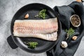 Raw cod fillet with thyme and herbs in a pan. Cooking fresh fish. Gray background. Top view Royalty Free Stock Photo