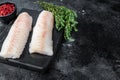 Raw cod loin fillet fish on marble board. Black background. Top view. Copy space Royalty Free Stock Photo