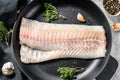 Raw cod loin with herbs in a frying pan. Gray background. Top view Royalty Free Stock Photo