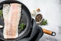 Raw cod loin with herbs in a frying pan. Gray background. Top view. Copy space Royalty Free Stock Photo