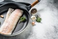Raw cod loin with herbs in a frying pan. Gray background. Top view. Copy space Royalty Free Stock Photo