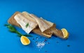 Salted dry codfish on white wooden backgroundRaw cod on a wooden board with pepper, dill and lemon. Blue background Royalty Free Stock Photo