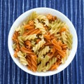 Multicolor spiral macaroni Pasta in a white cup on a striped white blue cloth background in the center. Close-up with Royalty Free Stock Photo