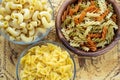 Multicolor spiral macaroni Wooden white and glass bowl with pasta on a textured wooden rustic board with a pattern