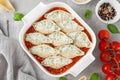 Raw conchiglioni pasta stuffed ricotta cheese and spinach with tomato sauce and parmesan cheese on top in a white baking dish