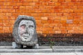 Concrete artifact along the city street with a brick wall background.