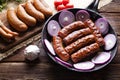 Raw and cooked sausage, pan, herbs and vegetables Royalty Free Stock Photo