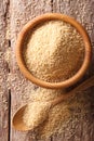 Raw Couscous in a wooden bowl and spoon close-up. vertical top v