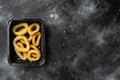 Raw Crispy deep fried onion or Calamari ring plastic pack, on black dark stone table background, top view flat lay, with copy Royalty Free Stock Photo