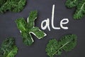 Raw curly-leaf kale cabbage inside letter K shaped plate, chalk inscription KALE and fresh green leafy vegetables on blackboard Royalty Free Stock Photo