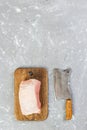 Raw cut of pork shoulder on board with knife or Kitchen ax. cleaver with fresh raw meat on gray concrete background Royalty Free Stock Photo