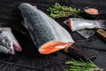 Raw cut salmon fish on a wooden cutting board with chef cleaver. Black Wooden background. Top view