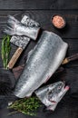 Raw cut salmon fish on a wooden cutting board with chef cleaver. Black Wooden background. Top view