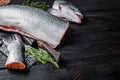 Raw cut salmon fish on a wooden cutting board with chef cleaver. Black Wooden background. Top view. Copy space