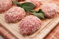 Raw cutlets or raw meatballs with ground beef in breadcrumbs and bay leaf on a wooden board. Dinner recipe from minced meat for