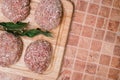 Raw cutlets or raw meatballs with ground beef in breadcrumbs and bay leaf on a wooden board. Dinner recipe from minced meat for