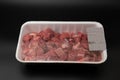 Raw diced meat chopped in cubes in a white styrofoam container with barcode on it isolated on black background with copy space Royalty Free Stock Photo