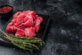 Raw diced red beef meat for Goulash on marble board. Black background. Top view. Copy space Royalty Free Stock Photo