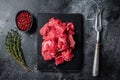 Raw diced red beef meat for Goulash on marble board. Black background. Top view Royalty Free Stock Photo