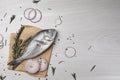 Raw dorado fish, spices and onion on white wooden table, flat lay