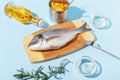 Raw dorado fish on a wooden board, ingredients for cooking and spices on a blue background