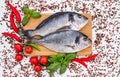 Raw dorado fish on wooden cutting board with peppercorns on white table