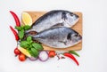 Raw dorado fish on yellow plate with peppercorns on white table, copy space