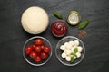 Raw dough and other ingredients for pizza on black table, flat lay Royalty Free Stock Photo