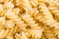 Raw dried fusilli pastas on pile detail as yellow textured background