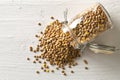 Raw, dry, uncooked brown lentil legumes in glass storage jar on white wood table background flat lay top view from above