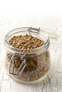 Raw, dry, uncooked brown lentil legumes in glass storage jar on white wood table background Royalty Free Stock Photo