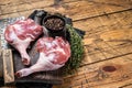 Raw duck legs with spices and chef cleaver on a wooden board. Wooden background. Top view. Copy space