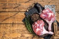 Raw duck legs with spices and chef cleaver on a wooden board. Wooden background. Top view. Copy space