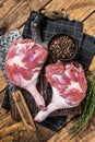 Raw duck legs with spices and chef cleaver on a wooden board. Wooden background. Top view