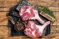 Raw duck legs with spices and chef cleaver on a wooden board. Wooden background. Top view