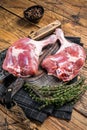 Raw duck legs with spices and chef cleaver on a wooden board. Wooden background. Top view