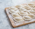 Raw dumplings on a wooden board on grey table. The process of making dumplings. Top view